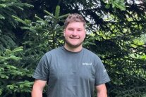 der neue Revierleiter Lukas Plechinger steht vor einer Tanne.